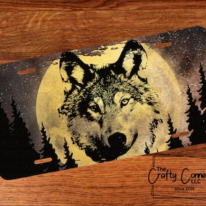 May include: A black and white wolf silhouette howling at a full moon with a starry night sky background. The moon is yellow and the trees are black.