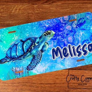 May include: A blue and green personalized license plate featuring a sea turtle swimming in a blue and green ocean with the name "Melissa" printed in blue.