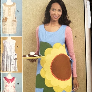May include: A sewing pattern for four different dresses. The pattern includes a dress with a sunflower design, a gingham dress, a floral dress, and a dress with a heart design. The pattern is from McCall's and the pattern number is 7625.