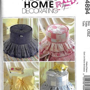 May include: A sewing pattern for four different styles of footstools. The footstools are covered in fabric with different patterns and colors, including pink and white gingham, blue and white gingham, and yellow fabric with a bow. The pattern is called McCall's Home Decorating and the size is OSZ.