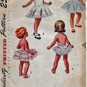 Peut inclure: Patron de couture vintage Simplicity pour une robe de fille. Le patron est pour la taille 3 et coûte 25 cents. Le patron montre une fille portant une robe blanche avec une jupe à volants. Le patron comprend également des instructions pour la confection de la robe.