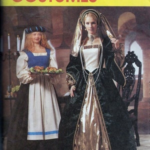 May include: Two women wearing medieval costumes. The woman on the left is wearing a blue and white dress with a white apron and a blue hat. The woman on the right is wearing a long green and gold dress with a white bodice and a gold headpiece. McCall's Costumes is printed on the top of the image.