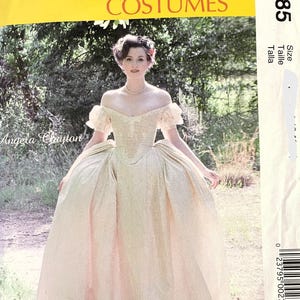 Peut inclure: Patron de couture McCall's Costumes M7885. Le patron présente une femme dans une robe crème à épaules dénudées avec une jupe ample. Le texte "Angela Clayton" est visible. L'arrière-plan est une scène extérieure floue.