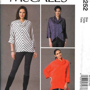 May include: McCall's M7252 sewing pattern featuring three cowl-neck tops. The tops are shown in white and black chevron stripes, a purple floral print, and a solid orange. The pattern includes the designer's name, Nancy Zieman.