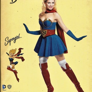 May include: A sewing pattern for a Supergirl costume. The pattern is from DC Comics Bombshells and is for sizes 6-14. The pattern includes a blue and red costume with a red cape and a yellow 'S' symbol on the chest. The pattern is from Simplicity.