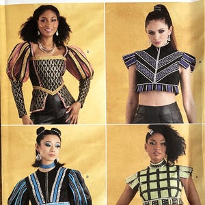 Peut inclure: Un patron de couture pour quatre costumes différents. Le patron s'appelle Simplicity Costumes et porte le numéro S9627. Les costumes sont un haut de style médiéval noir et or, un haut noir et violet avec un motif en V, un haut noir et bleu avec un motif en V et un haut à carreaux noir et vert.