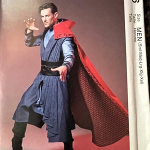 Puede incluir: Patrón de disfraces McCall's para hombre. La imagen muestra a una persona con un disfraz azul y rojo con capa. El patrón incluye la gama de tallas de pequeño a XXL.