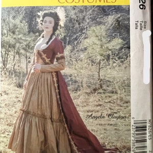 May include: A McCall's sewing pattern for a historical costume. The pattern is for a long, brown and red dress with a lace trim. The pattern is called "Angela Clayton" and the pattern number is M7826.