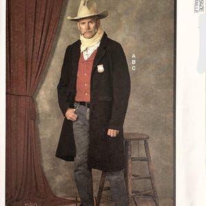 May include: McCall's Costumes pattern featuring a man in a cowboy costume. The costume includes a tan cowboy hat, a black coat, a red vest, and blue jeans. The background is a studio setting with a wooden floor and a stool.