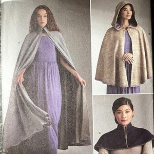 May include: Simplicity Costumes sewing pattern R12159. The pattern features three costume designs: a long grey cape, a hooded cape, and a short cape. The text "easy-to-sew" is visible. The pattern includes U.S. and Euro sizes.