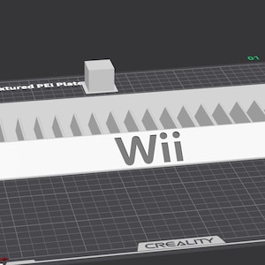 Puede incluir: Un objeto blanco impreso en 3D con la palabra "Wii" encima, apoyado sobre una superficie texturizada. El objeto tiene una base rectangular con una serie de cortes triangulares a lo largo del borde superior. Un pequeño cubo está posicionado al lado.
