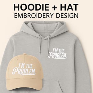 Op de afbeelding: Een lichtgrijze hoodie en een beige baseballpet. Beide items tonen de witte tekst "I'M THE PROBLEM". De hoodie heeft een voorzak en een capuchon met trekkoord. De pet heeft een gebogen klep. De tekst "HOODIE + HAT EMBROIDERY DESIGN" is inbegrepen.