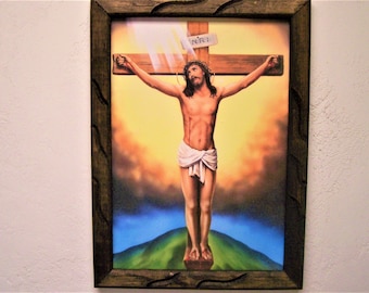 May include: A framed painting depicting a religious scene of Jesus Christ on the cross. The painting is set against a colorful background of clouds and a green hill. The inscription "INRI" is visible on the cross.