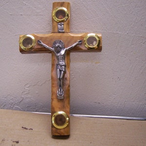 May include: A wooden crucifix with a silver Jesus figure. The cross has four gold-colored circles with glass inserts.