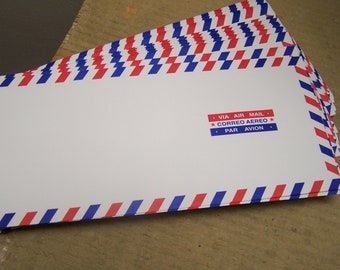 May include: Stack of white air mail envelopes with red and blue striped borders. The envelopes have text that reads "VIA AIR MAIL", "CORREO AEREO", and "PAR AVION".