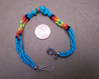 May include: A turquoise, black, yellow, orange, and red beaded bracelet with a silver clasp.