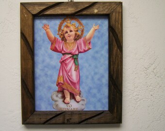 May include: A framed image of a child in a pink robe with a green sash, standing on a cloud with the text "YO REINARE" below. The child has a halo of gold leaves and is raising their arms.