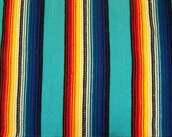 May include: A colorful woven blanket with stripes of red, orange, yellow, white, blue, and black on a turquoise background.