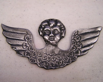 May include: A silver angel ornament with a cherub face and wings. The ornament is detailed with a textured, scaly pattern.