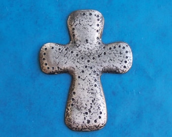 May include: A silver cross with a textured surface and a dotted pattern. The cross is on a blue background.