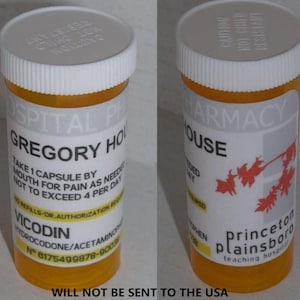 Puede incluir: Dos frascos de medicamentos naranjas con tapas blancas. Una botella tiene el nombre "Gregory House" y "Vicodin" impresos. La otra botella tiene el nombre "Princeton Plainsboro" impreso. El texto "WILL NOT BE SENT TO THE USA" está impreso en la parte inferior.