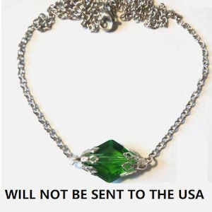 Puede incluir: Collar plateado con un colgante de cristal verde esmeralda facetado. El colgante en forma de diamante está engastado en una carcasa decorativa de metal plateado. La cadena es de estilo eslabones delicados con un cierre de mosquetón. El texto en la parte inferior dice "WILL NOT BE SENT TO THE USA".