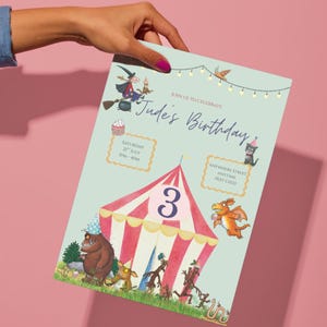 Peut inclure: Une invitation d'anniversaire bleu clair avec un design de chapiteau de cirque et le chiffre 3. L'invitation comprend le texte "Jude's Birthday" et les détails de l'événement. L'invitation est tenue par une main avec du vernis à ongles rose.