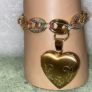 May include: A gold chain bracelet with a rainbow of colorful stones and a gold heart-shaped locket pendant.