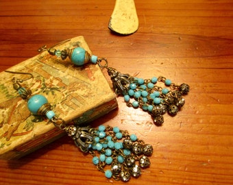 May include: A pair of turquoise and gold dangle earrings with a tassel design. The earrings feature turquoise beads and gold chain links.