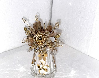 May include: A gold and clear glass decorative vase with a floral design. The vase is filled with gold wire and fabric flowers.