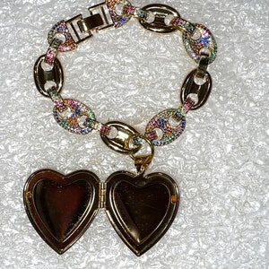 May include: A gold chain bracelet with a colorful, multi-faceted design. The bracelet has a heart-shaped locket attached to it.