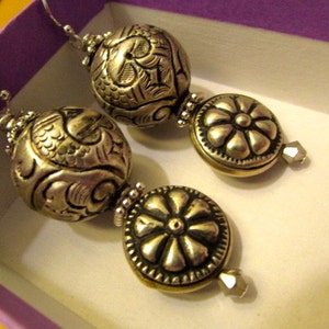May include: A pair of silver earrings with ornate, textured round beads and crystal accents.