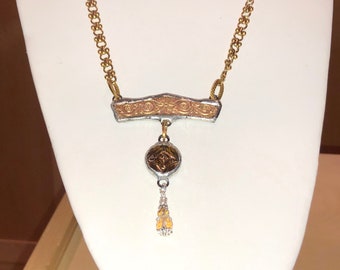 May include: A gold chain necklace with a silver pendant. The pendant has a gold-toned design and a small, dangling charm.
