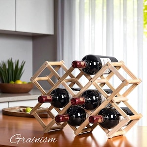 Puede incluir: Un botellero de madera que contiene seis botellas de vino tinto. El botellero es de madera clara y tiene un diseño en forma de diamante. Las botellas de vino son oscuras con papel de aluminio rojo en la parte superior. La palabra "Grainism" está en la parte inferior.