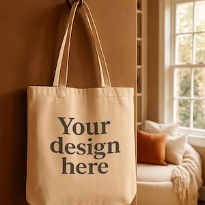 Może przedstawiać: Beżowa torba z nadrukiem "Your design here" w kolorze czarnym. Torba wisi na brązowym haczyku na brązowej ścianie. Tło obejmuje okno i część wypoczynkową.