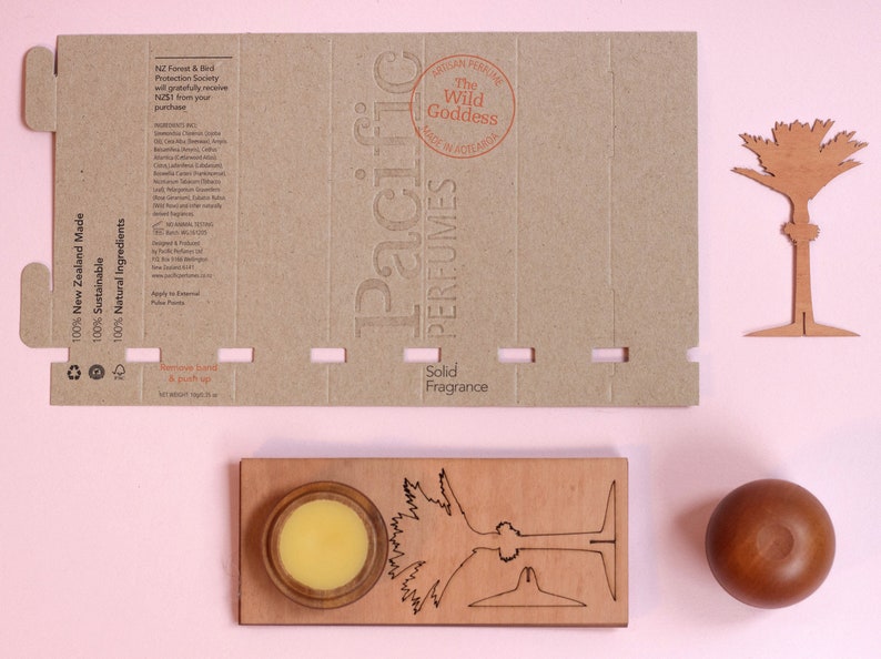 May include: A cardboard box with a brown background and white text. The text reads "100% New Zealand Made", "100% Sustainable", "100% Natural Ingredients", "Pacific Perfumes", "The Wild Goddess", "Solid Fragrance".