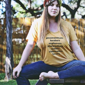 Flowy, soft mustard colored tshirt says "Peacemaker Healers Explorers Artists Visonaries Lovers" 
Printed with black ink. Perfect for any boho woman.
