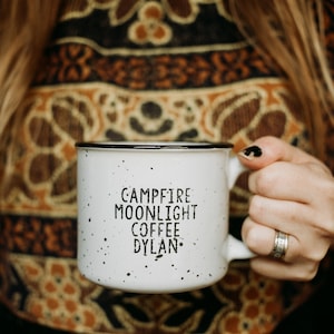 Ceramic coffee mug that says Campfire Moonlight Coffee Dylan.  White speckled 13oz campfire style mug. inspired by our love of Bob Dylan