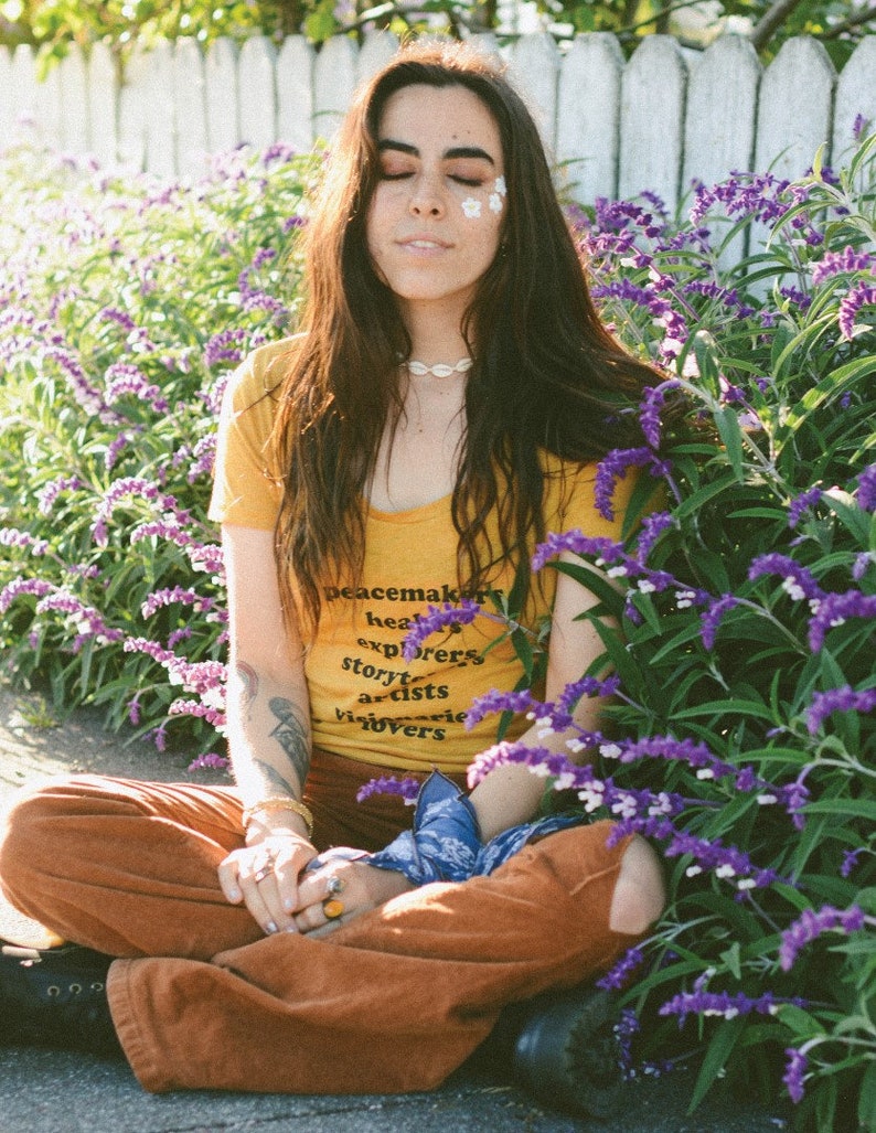 Flowy, soft mustard colored tshirt says "Peacemaker Healers Explorers Artists Visonaries Lovers" 
Printed with black ink. Perfect for any boho woman.