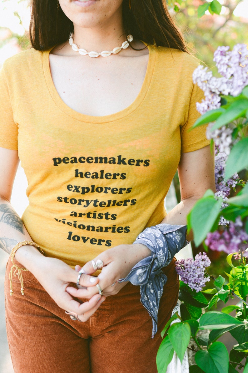 Flowy, soft mustard colored tshirt says "Peacemaker Healers Explorers Artists Visonaries Lovers" 
Printed with black ink. Perfect for any boho woman.