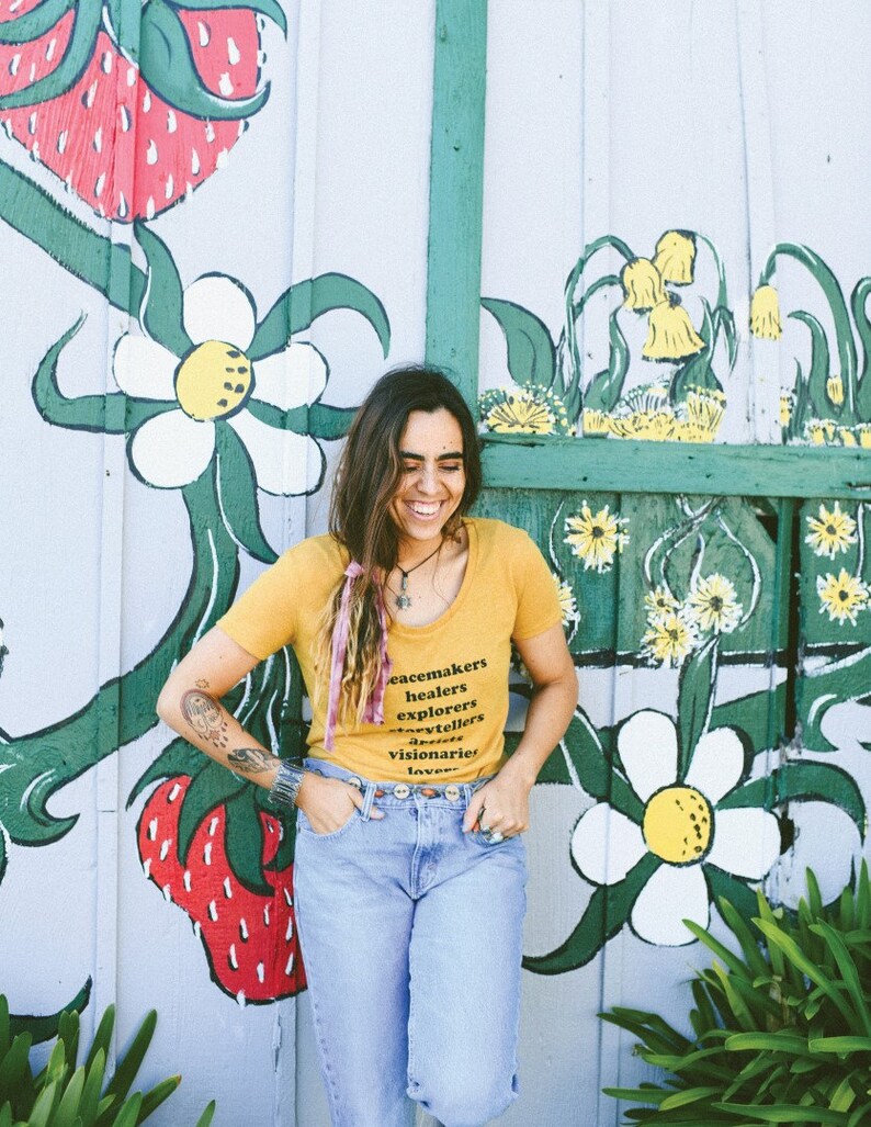 Flowy, soft mustard colored tshirt says "Peacemaker Healers Explorers Artists Visonaries Lovers" 
Printed with black ink. Perfect for any boho woman.