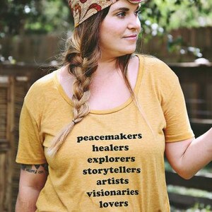 Flowy, soft mustard colored tshirt says "Peacemaker Healers Explorers Artists Visonaries Lovers" 
Printed with black ink. Perfect for any boho woman.