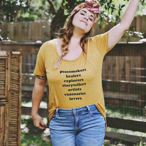 Flowy, soft mustard colored tshirt says "Peacemaker Healers Explorers Artists Visonaries Lovers" 
Printed with black ink. Perfect for any boho woman.