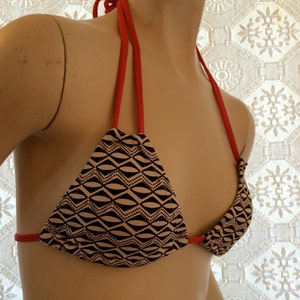 May include: A black and white geometric print bikini top with red straps.