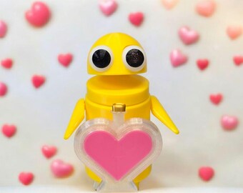 May include: A yellow robot toy holding a pink heart-shaped object. The robot has large black eyes and a simple design. The background is filled with pink hearts.
