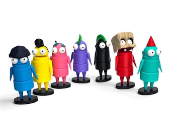 May include: A set of seven small, colorful, cylindrical figurines standing on black circular bases. Each figure has two large white eyes, thin arms, and distinct head features including hats, hair, and a paper bag mask in blue, yellow, pink, purple, black, red, and teal.