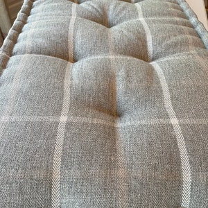 May include: Three gray and white checkered floor cushions. The cushions are tufted and have a soft, comfortable look.