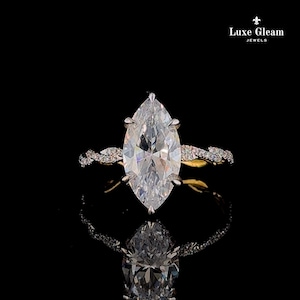 May include: A marquise-cut solitaire ring featuring a large, clear, faceted center stone set in a silver-toned metal prong setting. The band is crafted with a twisted, vine-like design encrusted with small, clear pavé stones. Luxe Gleam Jewels.