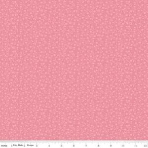 May include: A close-up of a pink fabric with a repeating pattern of small, light pink shapes. The fabric is a solid color with a subtle texture. A ruler is at the bottom of the image, showing inches.