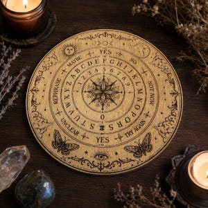Peut inclure: Une planche de spiritisme circulaire en bois avec une rose des vents gravée au centre, entourée de l'alphabet, des chiffres de zéro à neuf, et des mots Yes, No, Maybe, Rephrase, Unclear, Not Now, et Try Again, avec des motifs de papillons et célestes.